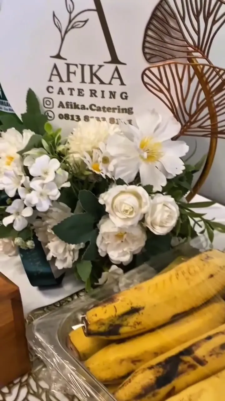 Papan nama Afika Catering dengan rangkaian bunga putih
