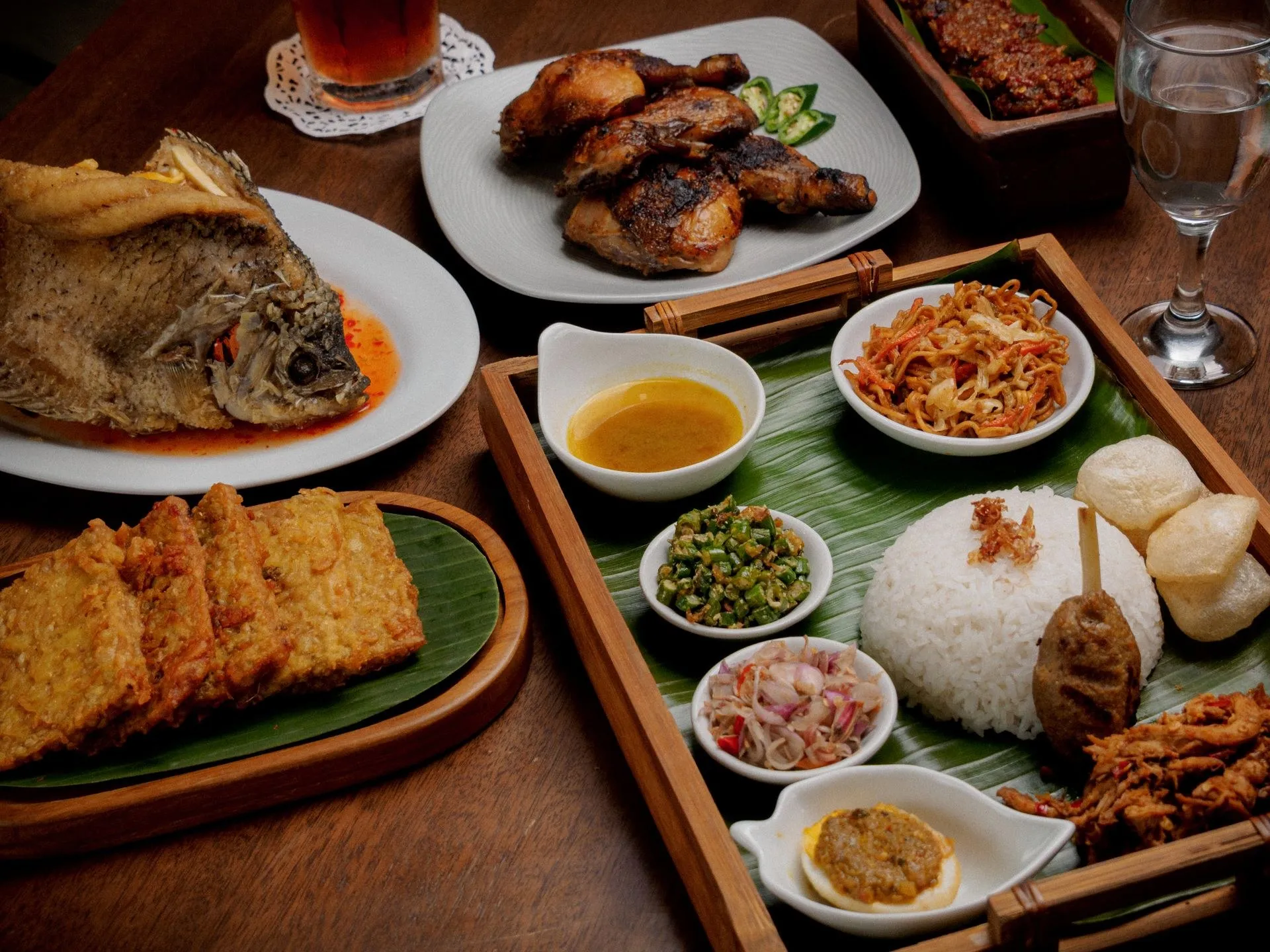Ikan goreng, ayam bakar, dan lauk Nusantara di atas meja