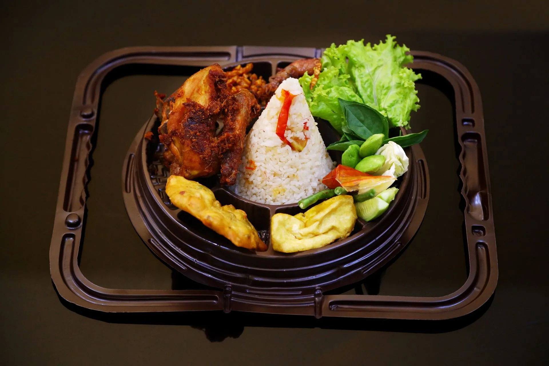 Nasi dengan ayam goreng dan lalapan dalam kemasan box