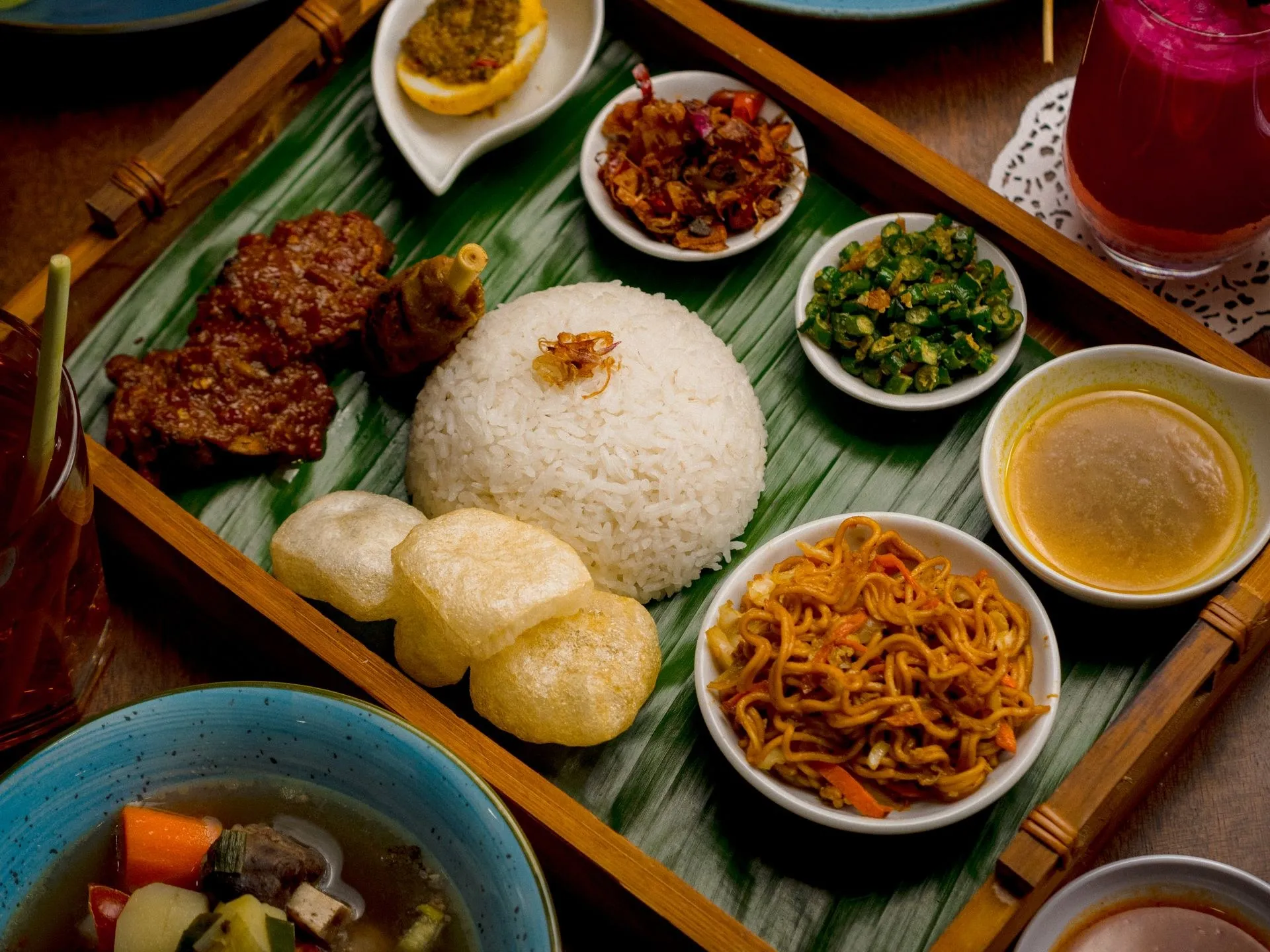 Nasi dengan lauk dalam mangkuk kecil di atas daun pisang