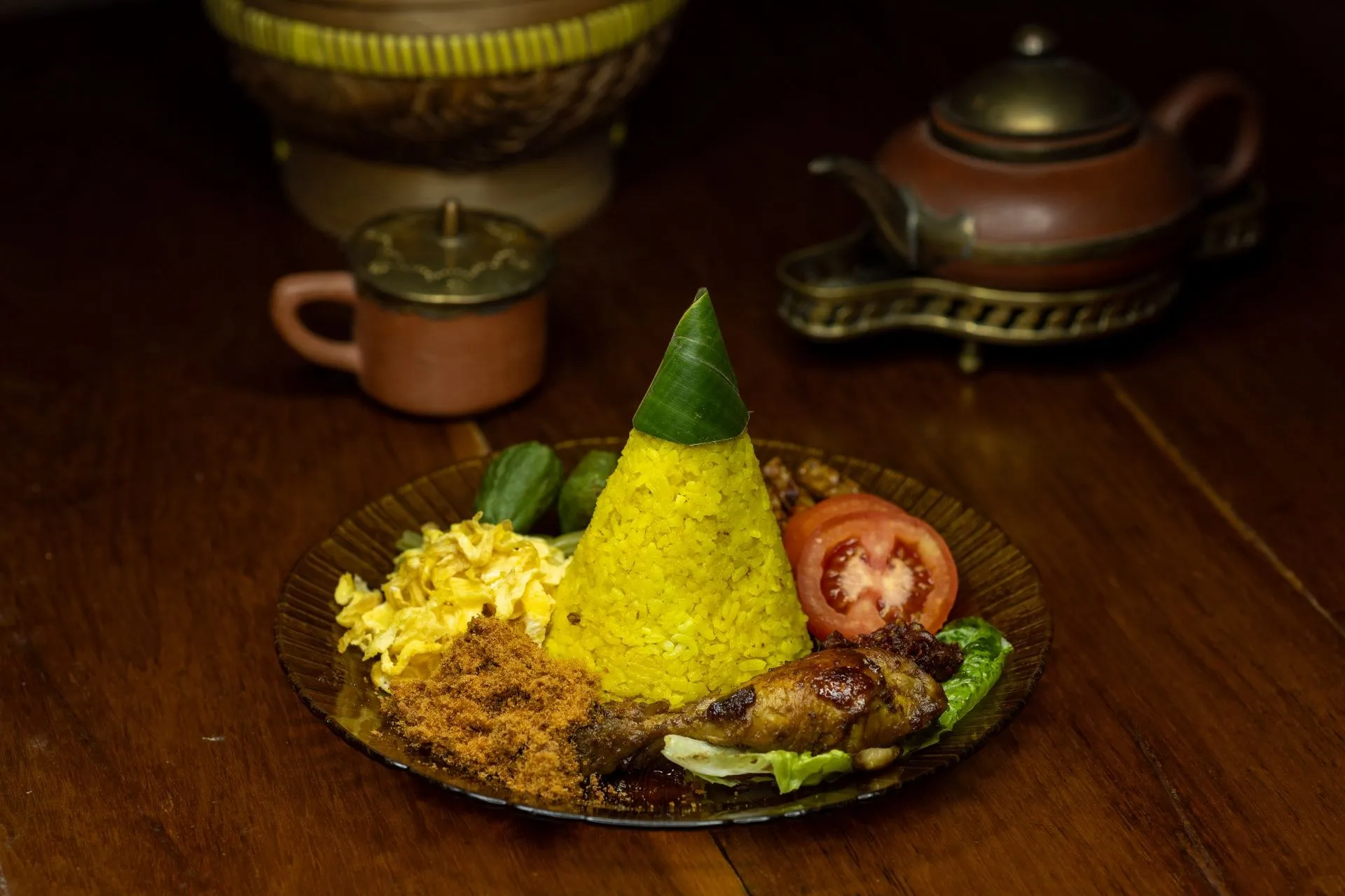 Nasi tumpeng kuning dengan lauk pendamping di atas meja kayu