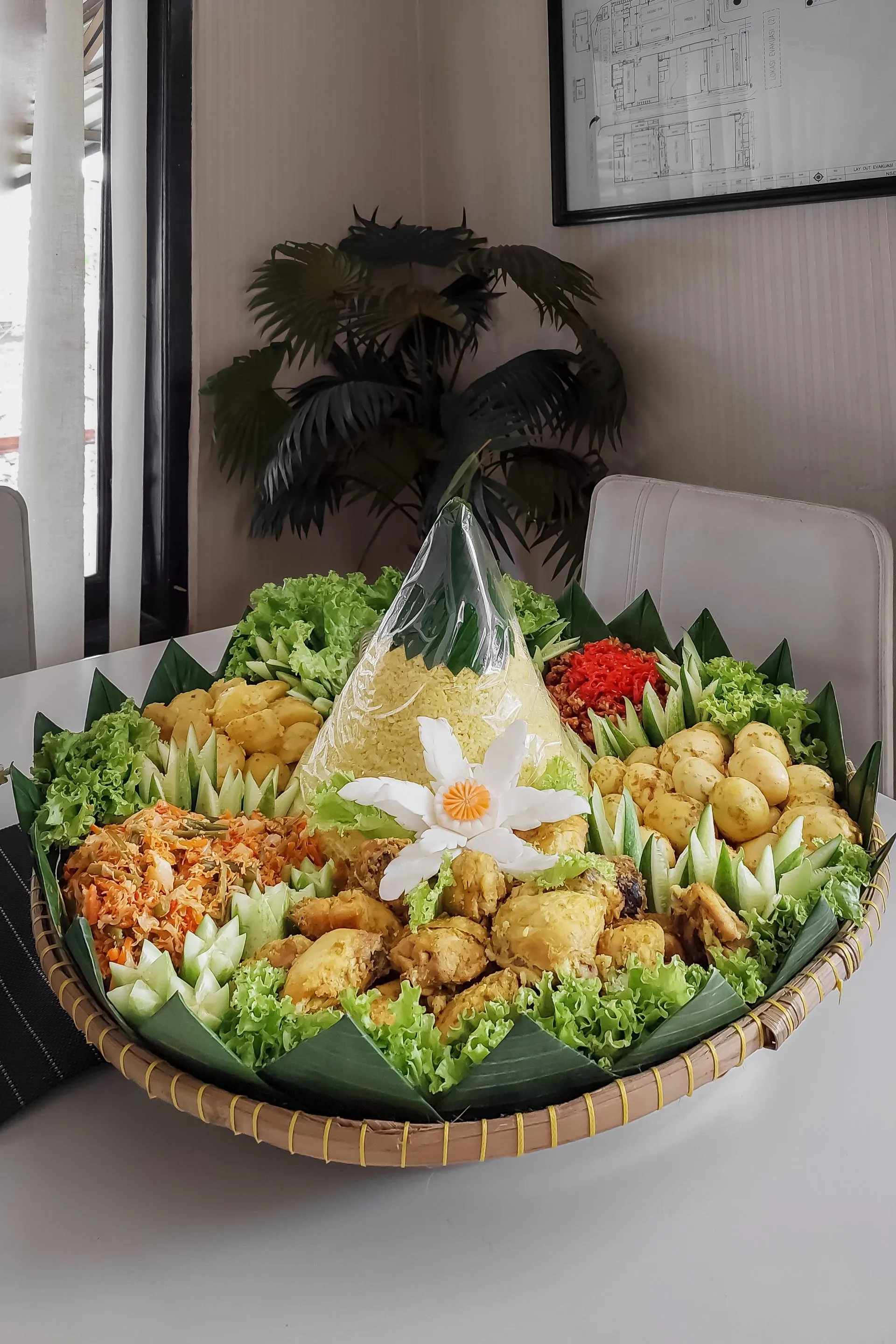 Tumpeng besar dalam tampah dengan aneka lauk